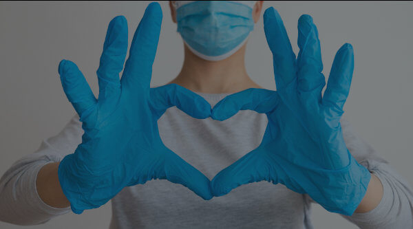 Gloved individual with hands in a heart shape.